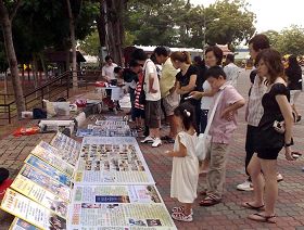 游客在观看展板,签名谴责中共迫害