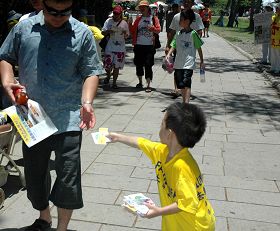 七月十八日屏东学员在鹅銮鼻讲真相,图为小弟子分送真相材料给行人