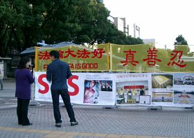 法轮功学员(左)在向行人讲法轮功真相