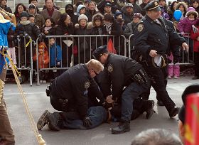 法拉盛新年游行活动中,一华裔男子从观众群中冲到法轮功队伍的前面,拉扯横幅并折断横杆。三个警察立即冲上去将其制服并逮捕。