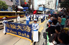 法轮功反迫害游行队伍经过铜锣湾闹市,吸引道路两旁许多人驻足观看。