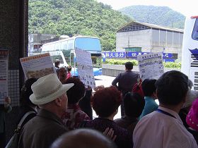 法轮功学员在中国游客等候游览车之处,传递真相信息