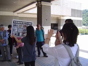中国游客拿起相机,拍摄真相展板