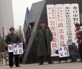 陈艳的父亲打出了“还我女儿”的牌子,陈的女儿也打出了“还我父母”的牌子