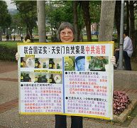 今年七十五岁的林昭吟神清气爽高举法轮功的真相展板,笑容灿烂迎接着大陆游客