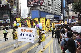 '庆祝世界法轮大法日的队列走过铜锣湾闹市,吸引众多中外途人驻足观看。'