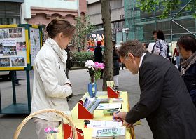 法轮功摊位前,前来签名支持法轮功学员反迫害的人们络绎不绝。