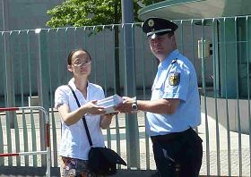 法轮功学员向德国总理递交了五万七千六百个签名,抗议中共活体摘取法轮功学员器官。背景为德国总理府。