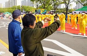 韩国法轮功学员在博士谷艺术节庆典上演示功法,市民也跟着学炼动作