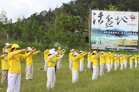 靠近日月潭入口的鱼池乡长红茶休闲广场旁,近百位法轮功学员演示功法。
