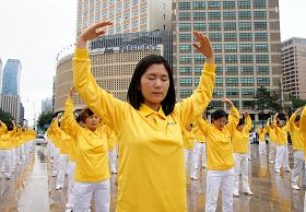 '二零一一年七月十六日,韩国八大市民团体与法轮功学员冒雨在首尔广场举行联合集会,谴责中共对法轮功长达十二年的人权迫害。图为韩国法轮功学员集体炼功场面。'