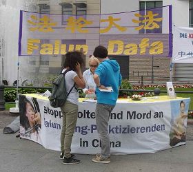 在著名景点勃兰登堡门前,不断有人来到法轮功摊位前仔细询问,并签名反迫害