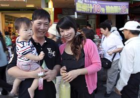 '一对年轻夫妇抱着小孩,很高兴要到了莲花和材料,碰到摄影记者,要求拍照留念,并全家高喊法轮大法好。'