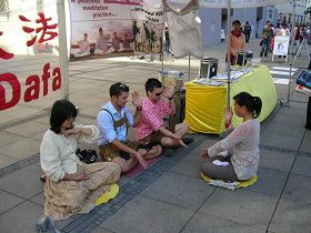 '身穿巴伐利亚传统服装的两位小伙子,正跟着法轮功学员炼习功法。'