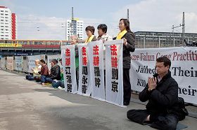 '法轮功学员手持条幅,上书:法办江泽民、周永康、刘京、罗干。'