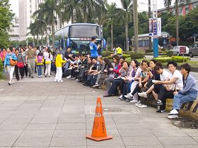 '整团大陆观光客排排坐,听法轮功学员讲真相外,频频对这盛大的炼功场面感到惊叹'
