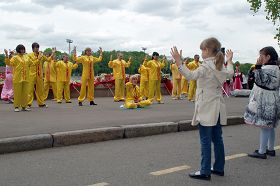 大法弟子祥和的炼功场面,吸引着这二位小朋友认真学炼。