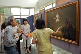 '台湾艺术家黄钜太(左一)聚精会神听解说员介绍画作。'
