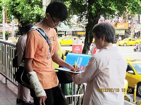 一位青年右手受伤包扎,仍以左手签下名字。