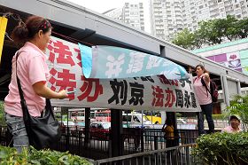 穿着粉红色制服的“香港青年关爱协会”中共帮凶,用带来的横幅掩盖法轮功学员的横幅,故意挑衅香港法轮功学员。