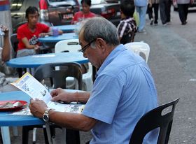 老居民拿到法轮功真相资料后,开始认真地阅读起来。