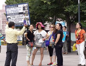 '退休宜兰教师李光辉正向中国游客讲真相(身着黄色衬衫拿展板)'