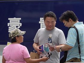 '李香兰(左一着粉色衣服者)发《九评共产党》及法轮大法简介给大陆观光客'