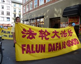 丹麦法轮功学员参加游行,微笑着向沿途民众展示“法轮大法好!”