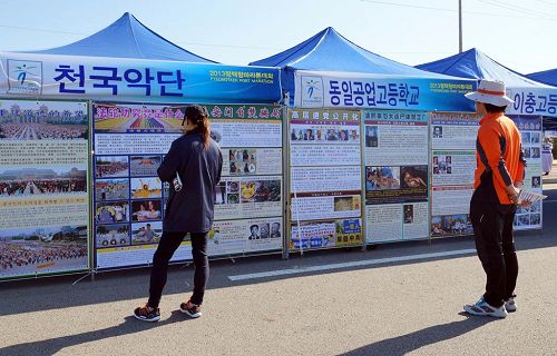 '马拉松活动场设置的天国乐团展位上,参赛选手们和市民们了解法轮功真相。'