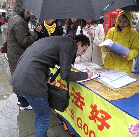 '在伦敦圣马丁广场,英国民众在雨中仍踊跃地在给国会议员的请愿信上签名'