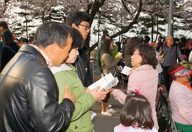 '来观赏春花的游客们,接过传单在认真阅读'