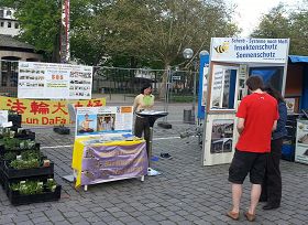 '法轮功学员向路过摊位的人展示功法,讲真相'