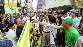 '六月二日,恶党团伙侵扰旺角行人专用区的法轮功真相点,激起极大民愤。青关会头目林国安(穿深蓝色衣服手持横幅)受到民众强烈谴责'