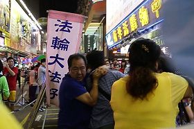 '图4:黑帮青关会头目林国安(左一,蓝衫者)勒住一名市民脖子,女恶霸肖小容(右一,黄衫者)则用脚狠踢,部份法轮功学员也被恶徒殴打。'