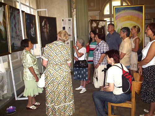 图:乌克兰哈尔科夫市的真善忍美展上,观众欣赏画作,聆听导览。
