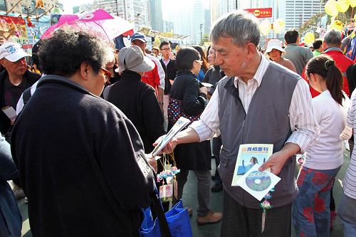 '在年宵真相摊位前,法轮功学员向民众送上精美的小莲花及真相小册子。'