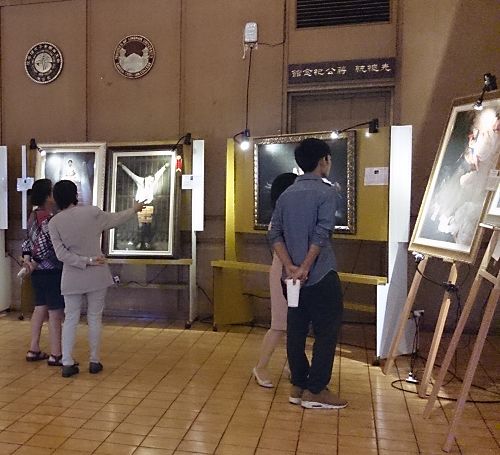 美展会场人们观看画作,并听导览解说