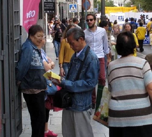 图3:华人在法轮功学员游行队伍经过之后仍在阅读接过的真相传单