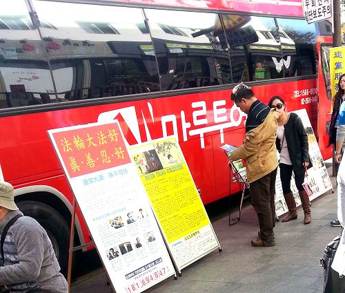 在韩国首尔景点,旅游团的巴士旁的真相展板