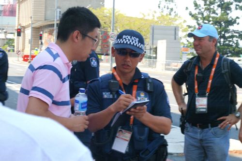 图5:中共派来干扰法轮功学员拉横幅的中国留学生们一一被澳洲警察要求登记护照内容,图为组织学生来的负责人之一正在被登记。