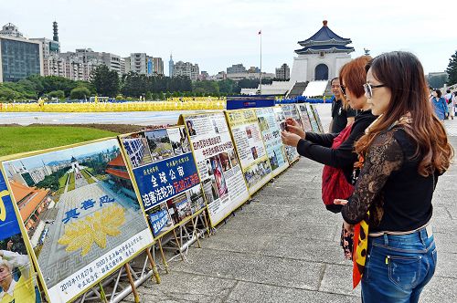 图11-12:大陆游客将法轮功学员排字盛况的真相展板内容照下,有的和展板合影,打算带回国内给亲友看。