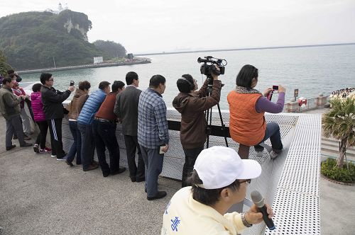 几位大陆游客快快登上雄镇北门高处看台,拿起手机、相机拍下法轮功学员给师父拜年的合照。