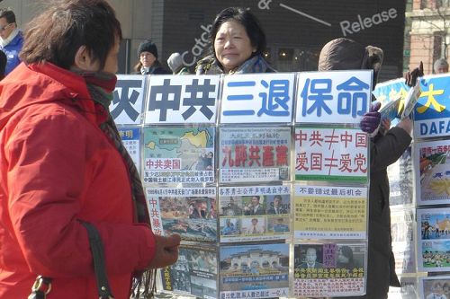 纽约自由女神像附近,法轮功学员向游客展示真相展板。