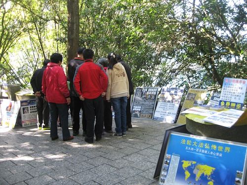 玄光寺步道上摆放很多真相展板,大陆游客正聚精会神的观看并讨论。