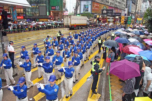 图7-8.由天国乐团引领的法轮功学员的游行,在风雨中照样吸引大批港民及中西游客冒雨观看。