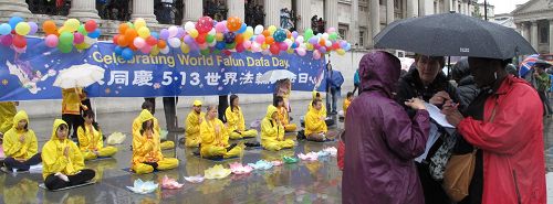 活动过程中风雨骤降,法轮功学员不为所动,坚持炼功和讲真相,民众冒雨了解真相和签名