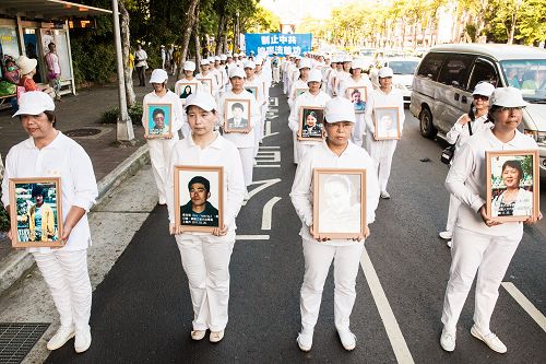 学员衣着净白素服,手捧被迫害致死的大陆法轮功学员照片,圣洁静肃行进