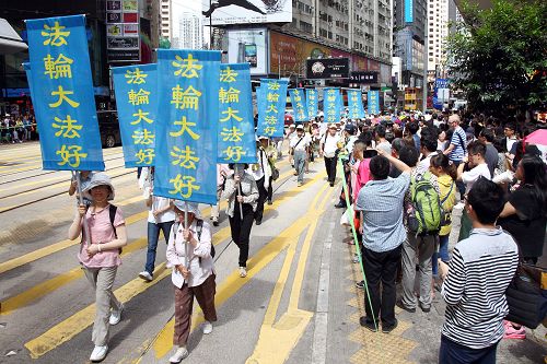 图9-14:法轮功阵容庞大整齐的游行队伍吸引中西游客及港民驻足观看,纷纷举起相机、手机拍照。