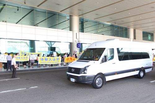 二十一日,当中共江西省委书记强卫(白色坐车)一到桃园机场接机大厅,便被法轮功学员当面告知:“你被告了!停止迫害法轮功。”