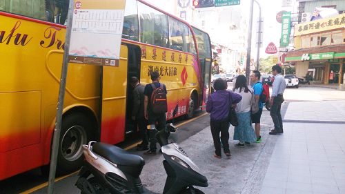 法轮功学员(中间穿紫色上衣,手拿资料者)给正在上车的大陆游客派发真相资料。